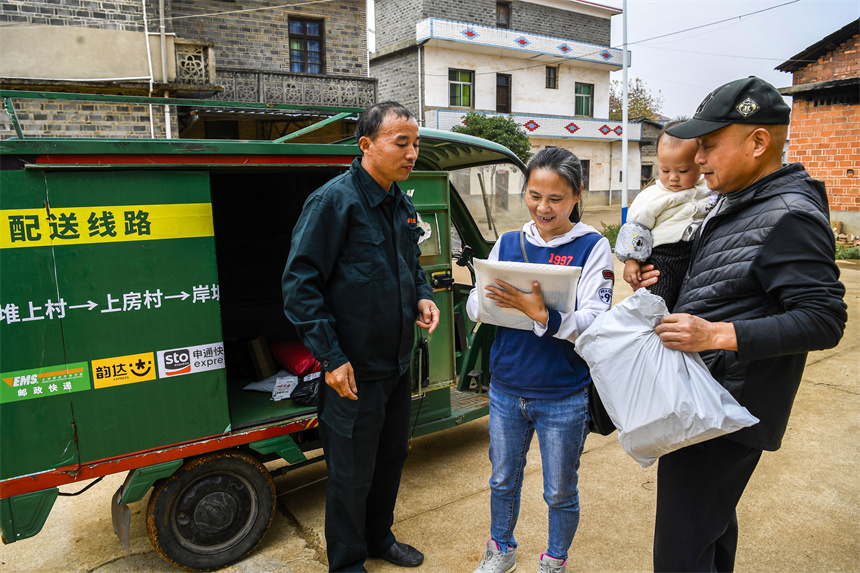 快遞員將包裹送至塘下村村民手中。周亮攝
