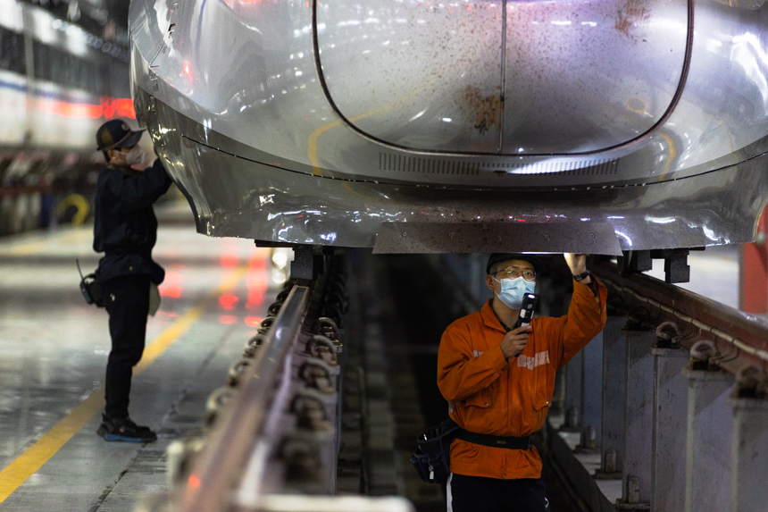 南昌西車輛段的兩名動車機械師正在對歸來的列車進行檢修。李桐攝