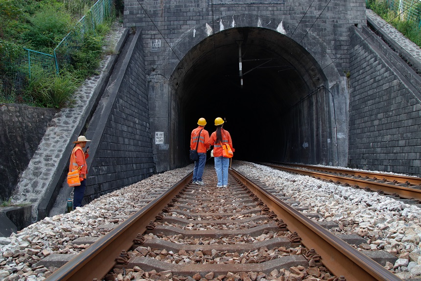 女橋隧工何卓卿與父親徒步進入隧道開展春運設備檢查工區。羅毅攝