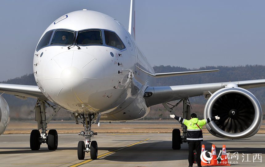 地勤人員引導C919進入停機位。 人民網 時雨攝