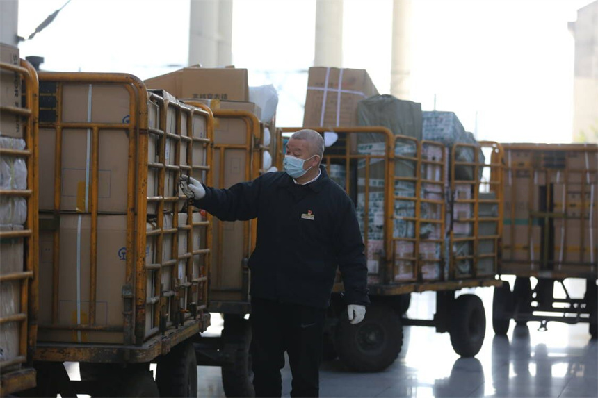 張細毛對裝載貨物的行李車進行檢查，確保護欄完全關閉。 張倩攝