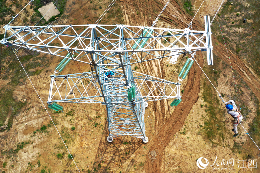 電網工作人員正在塔頂進行牽線作業。人民網 時雨攝