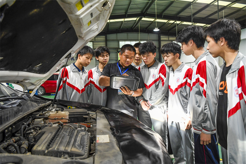 老師在向學生演示新能源汽車的維修技巧。周亮攝