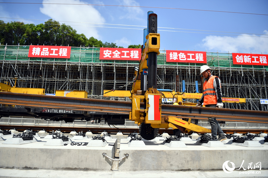 浮梁東站內多線鋪軌一體機正在將鋼軌鋪入無砟軌道承軌槽中。 人民網記者 時雨攝