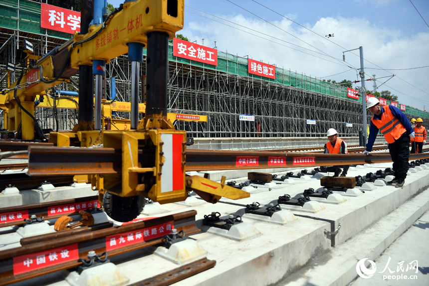 浮梁東站內多線鋪軌一體機正在將鋼軌鋪入無砟軌道承軌槽中。 人民網記者 時雨攝