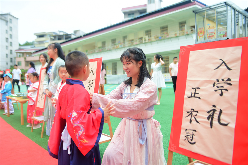 小朋友在老師的指導下端正衣冠。呂春華攝