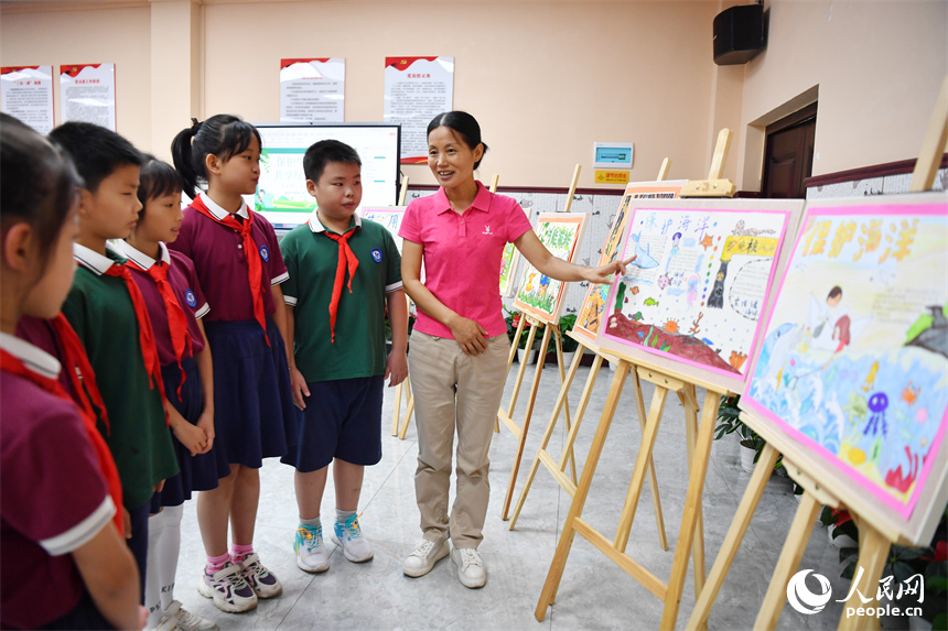 通過學生們的畫作，鄒友琴向大家講解環境保護的必要性。 人民網記者 時雨攝