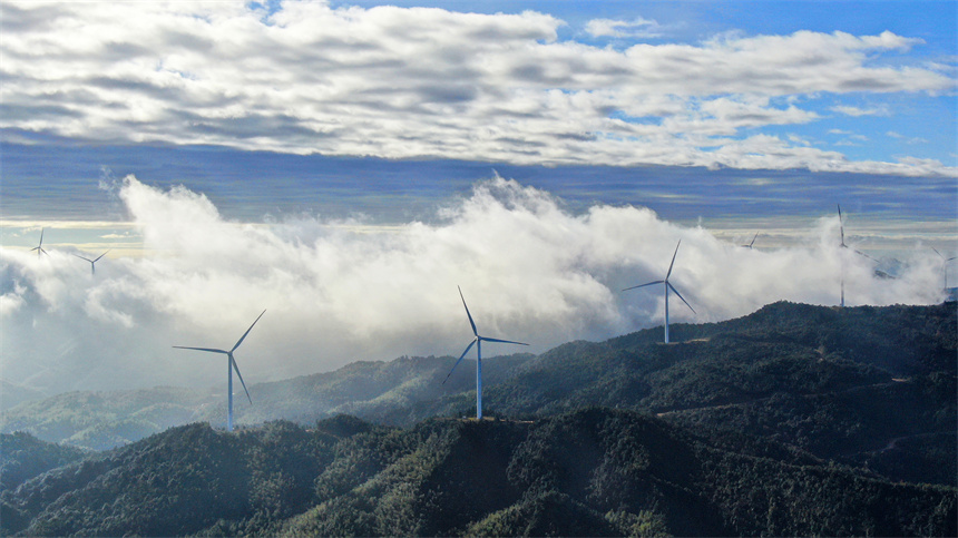一臺臺風力發電機矗立在群山之巔，蔚為壯觀。詹繼成攝