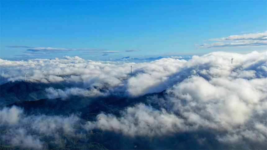 一臺臺風力發電機矗立在群山之巔，蔚為壯觀。詹繼成攝