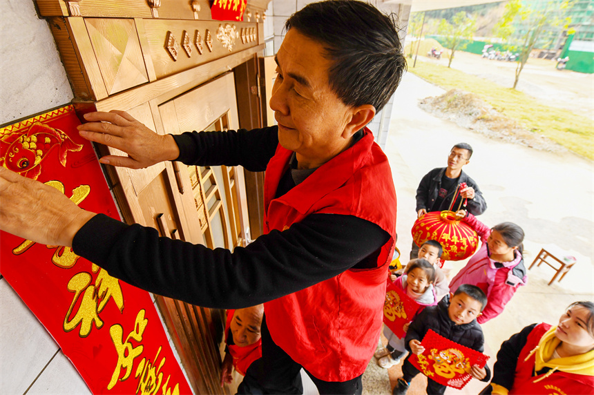 黨員志愿者為村民貼春聯。詹繼成攝 