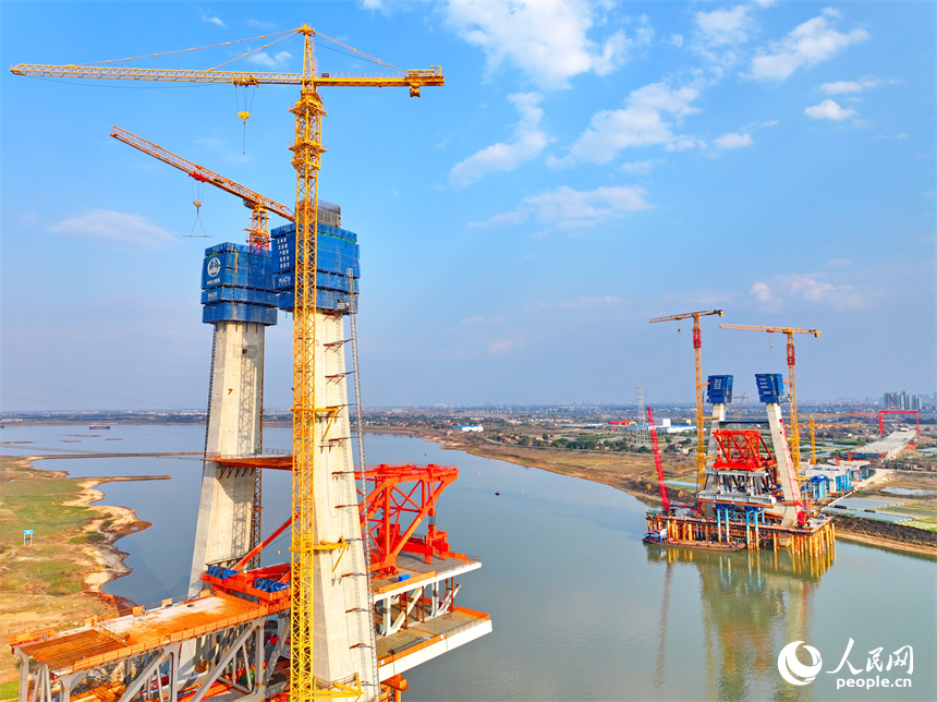 南昌市東湖區揚子洲鎮贛江河畔塔吊矗立，設備有序運轉，工人在隆興大橋項目工地忙碌。人民網 朱海鵬攝