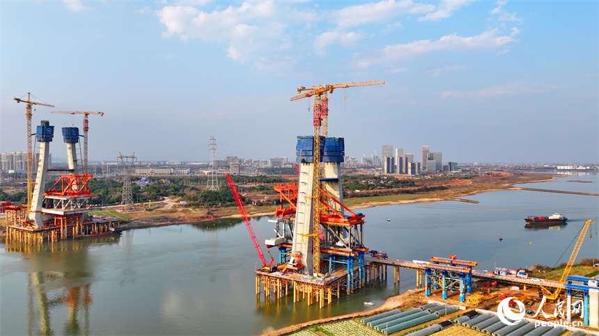 南昌市東湖區揚子洲鎮贛江河畔塔吊矗立，設備有序運轉，工人在隆興大橋項目工地忙碌。人民網 朱海鵬攝