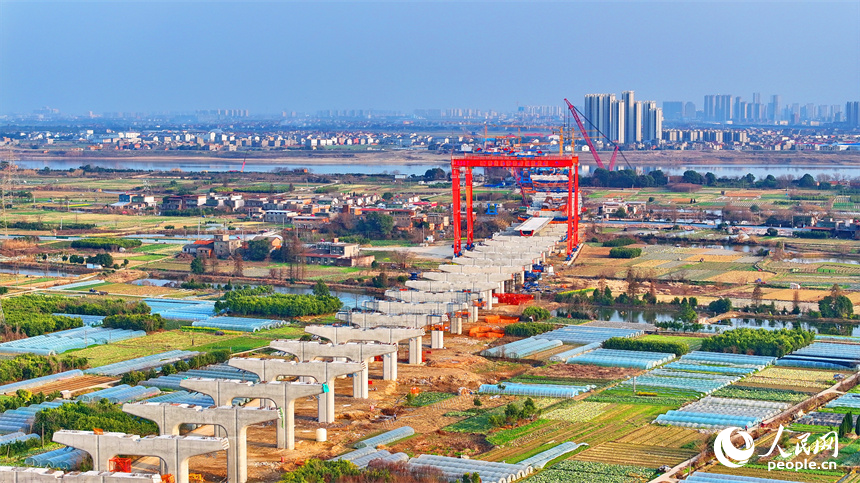 南昌市東湖區揚子洲鎮贛江河畔塔吊矗立，設備有序運轉，工人在隆興大橋項目工地忙碌。人民網 朱海鵬攝