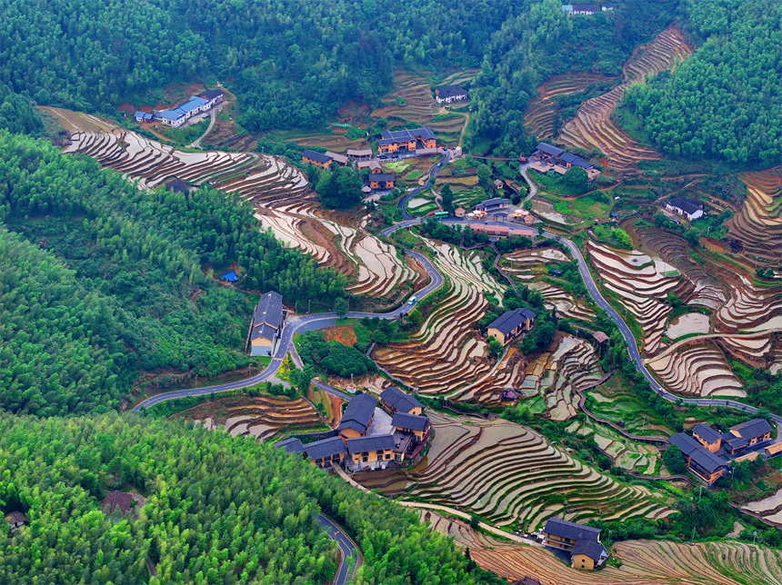 贛州市崇義縣上堡鄉，層層疊疊的梯田與森林、民宿、公路相互映襯，夏日綠色生態美景怡人。人民網 朱海鵬攝