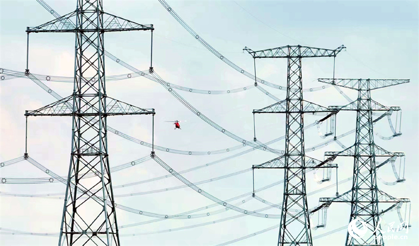 直升機穿梭在特高壓電線旁開展特高壓工程驗收作業。人民網記者 時雨攝
