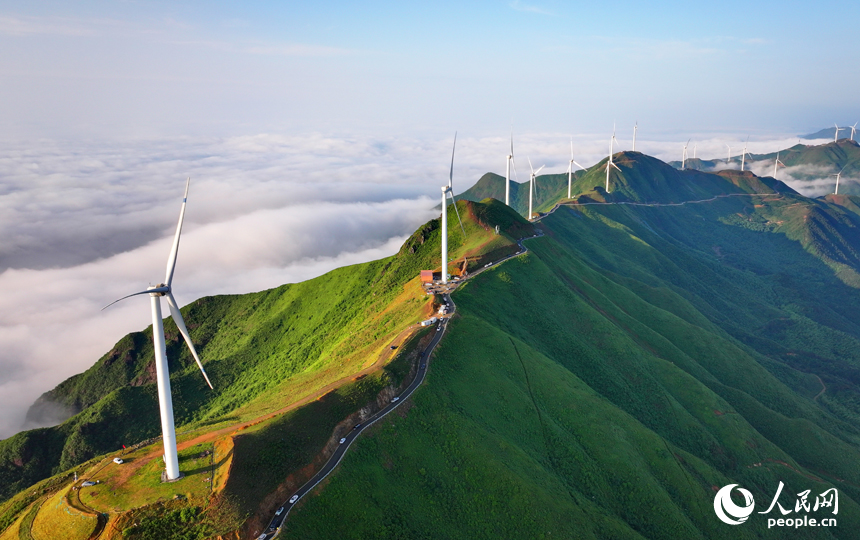 在吉安市遂川縣左溪鎮洋溪村俯瞰雙溪草山，數十臺風力發電機迎風旋轉，與朝霞、云海、青山交相輝映，風景如畫。人民網 朱海鵬攝