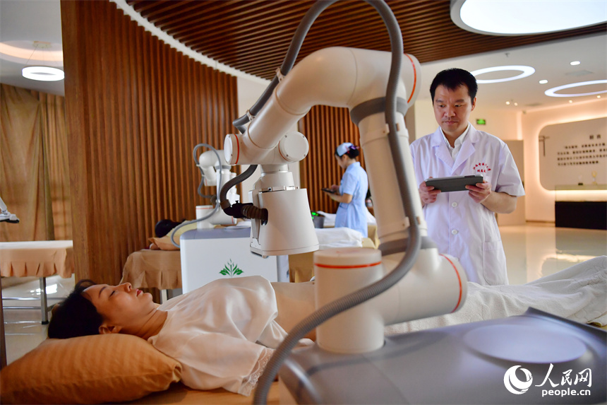 江西中醫藥大學附屬醫院的醫生正通過平板電腦上的App操作熱敏灸機器人，對病人進行熱敏灸的治療。人民網記者 時雨攝