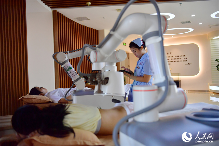 江西中醫藥大學附屬醫院的護士正通過平板電腦上的App操作熱敏灸機器人，對病人進行熱敏灸的治療。人民網記者 時雨攝