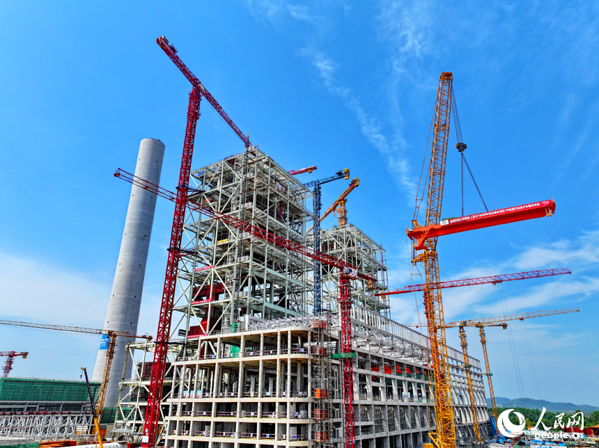 江西贛能上高綜合能源服務項目建設現場塔吊林立，施工人員在吊裝清潔煤電項目1號機組汽機房行車設備。人民網 朱海鵬攝