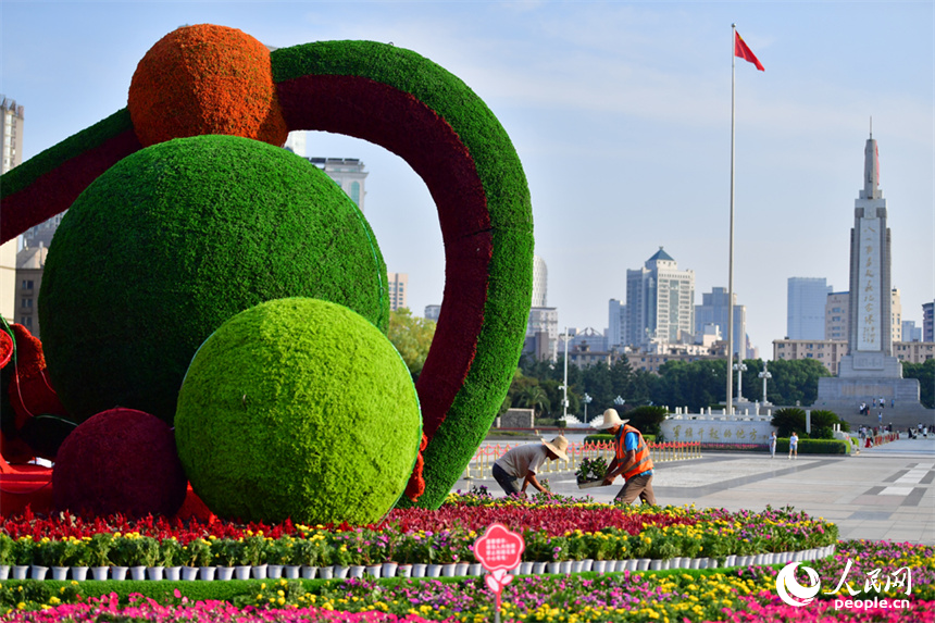 八一廣場上，施工人員正在布置國慶立體花卉造型。人民網記者 時雨攝