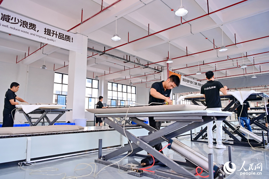 贛州市南康區經濟開發區的一家軟體家具生產企業車間內，工人在加緊制作軟包實木家具。人民網 朱海鵬攝
