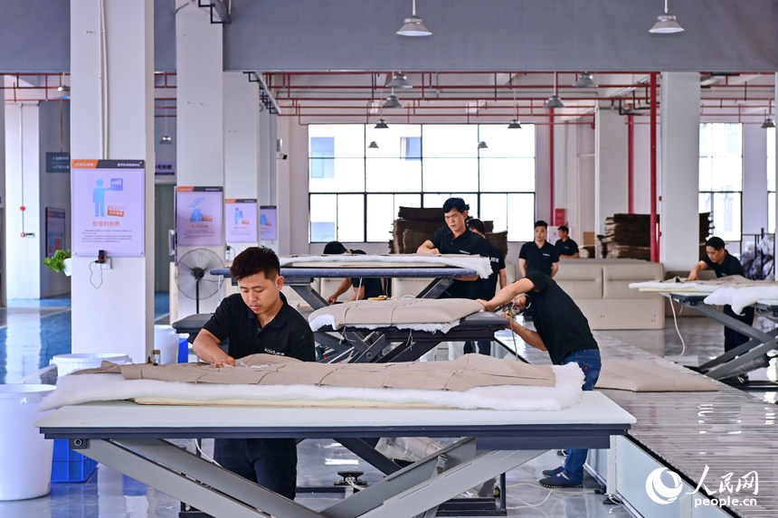 贛州市南康區經濟開發區的一家軟體家具生產企業車間內，工人在加緊制作軟包實木家具。人民網 朱海鵬攝