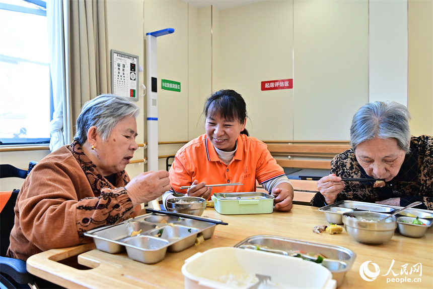 吉安市廬陵新區鳳凰社區養老中心，護工在陪同老人用餐。人民網 朱海鵬攝