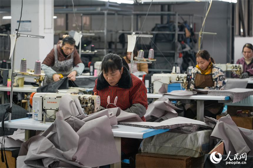 工人們正在縫合行李箱里布。人民網 涂詩軒攝