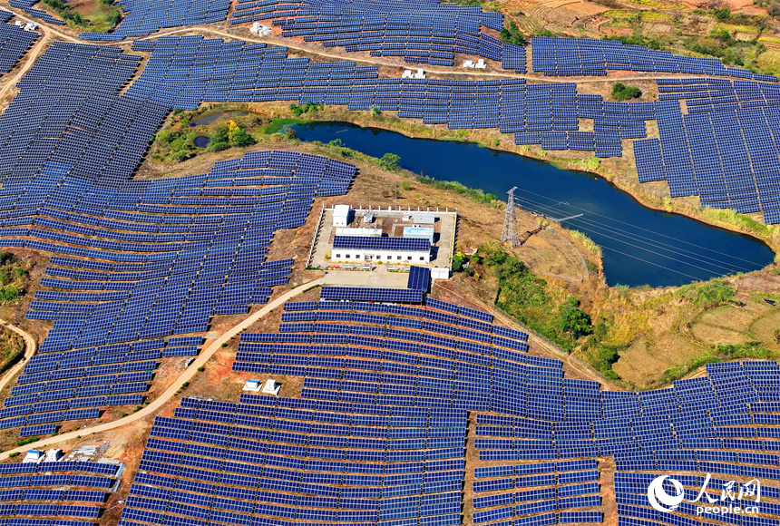 贛州市信豐縣正平鎮的一處農光互補光伏發電基地，太陽能光伏板與青山綠樹、村莊田園相映襯。人民網 朱海鵬攝