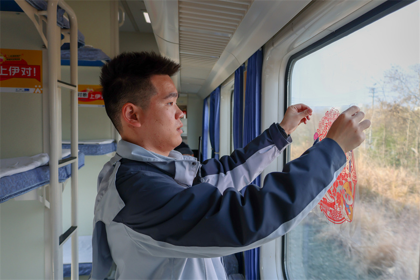 圖為K4280次旅客列車乘務員在車廂內張貼窗花，營造溫馨的乘車氛圍。 黃鐘濱 攝