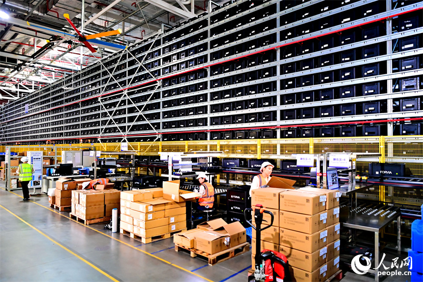 豐城市高新技術產業園區的一家汽車電子企業內，AGV運輸車來回運轉有序作業，工人在加工車載電子產品。人民網 朱海鵬攝