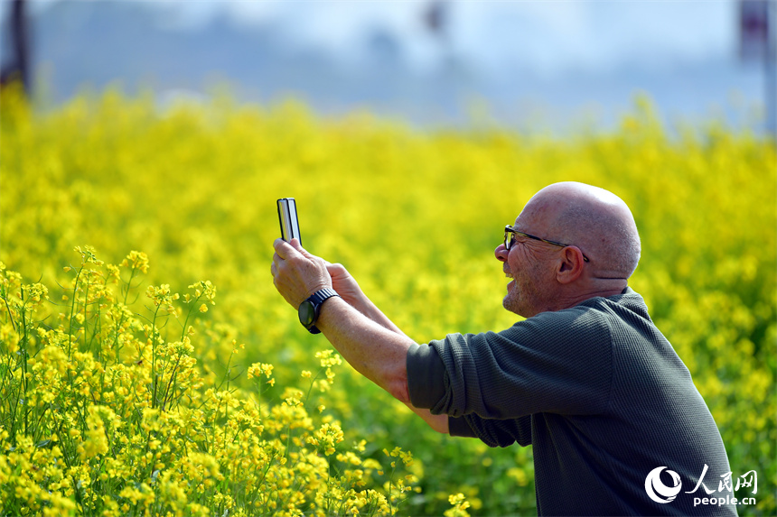 九龍湖濕地公園內，一名外國游客正在花海中賞花拍照。人民網記者 時雨攝
