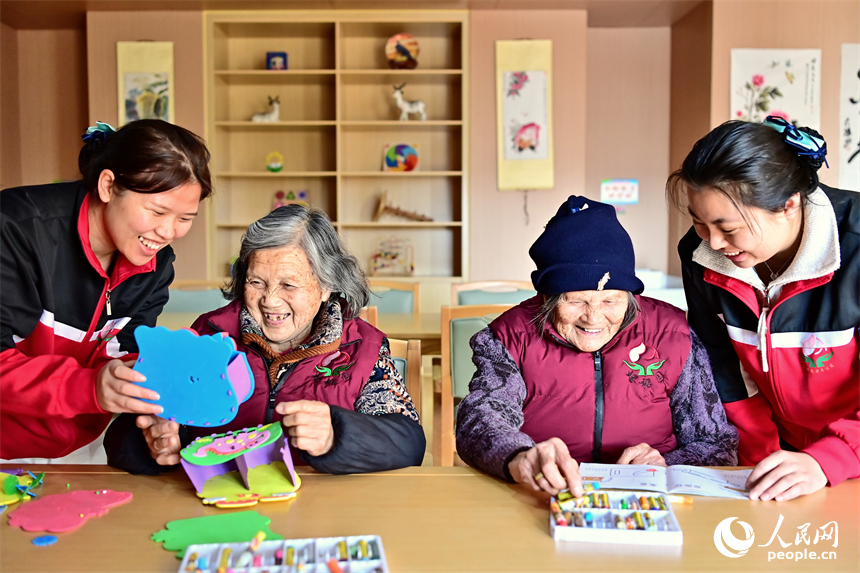贛州市南康區蟠桃園老年公寓，護工在陪伴老人制作手工擺件。人民網 朱海鵬攝