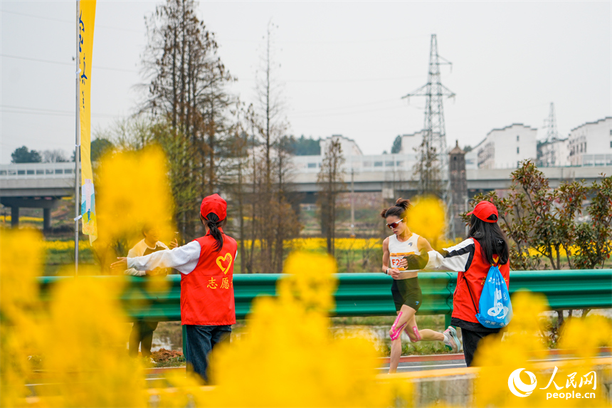 參賽選手在路邊油菜花的陪伴下，迎著微風奮力奔跑。人民網 涂詩軒攝