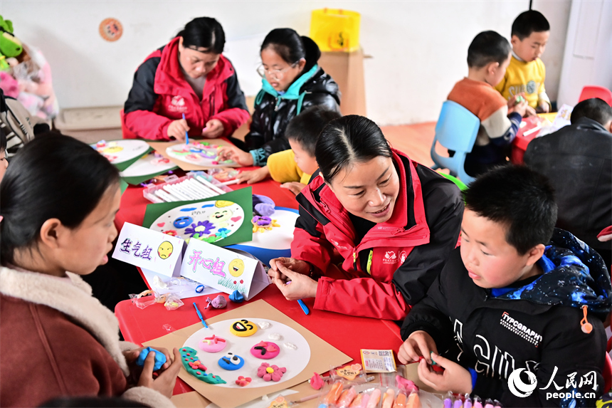 撫州市樂安縣湖溪鄉梅溪村“幼吾幼”少兒之家，當地慈善總會的志愿者和農村留守兒童一起交流互動，進行趣味粘土手工制作游戲。人民網 朱海鵬攝