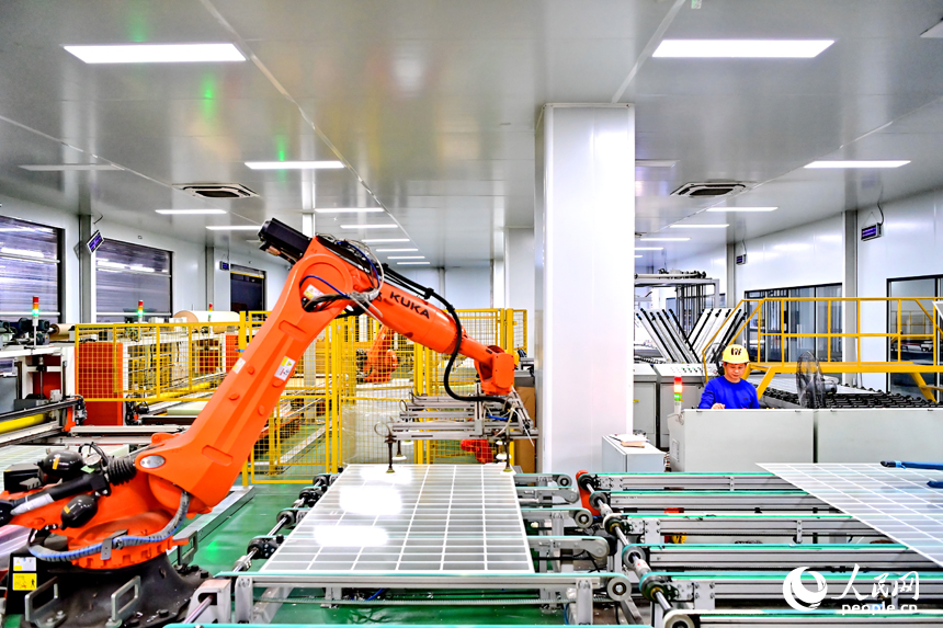 贛州市定南縣的一家新材料有限公司智能制造車間內，機器人手臂在來回循環作業，工人忙著加工光伏玻璃面板。人民網 朱海鵬攝