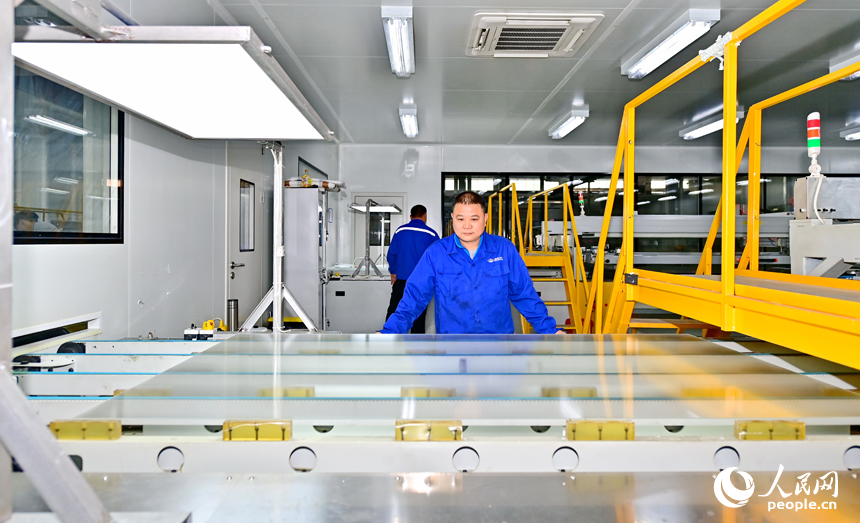 贛州市定南縣的一家新材料有限公司智能制造車間內，工人忙著加工光伏玻璃面板。人民網 朱海鵬攝