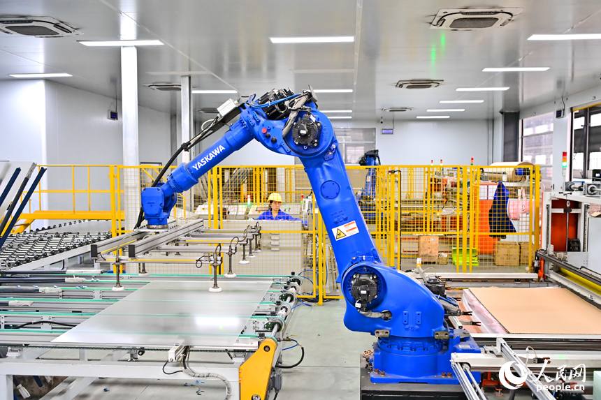 贛州市定南縣的一家新材料有限公司智能制造車間內，機器人手臂在來回循環作業，工人忙著加工光伏玻璃面板。人民網 朱海鵬攝