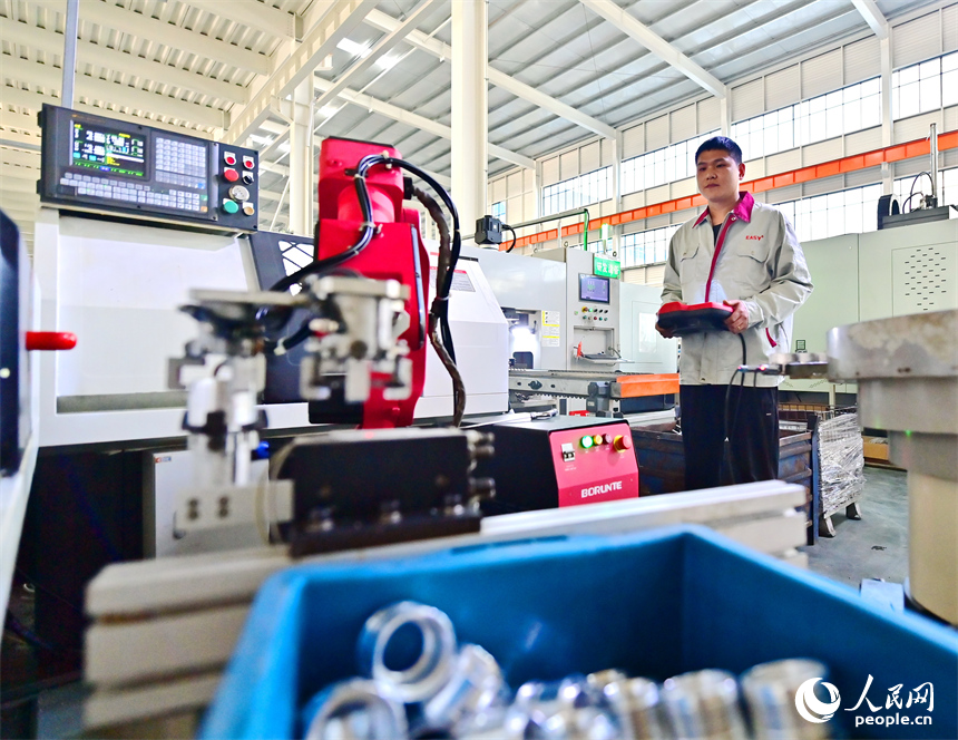 上饒市弋陽縣高新技術產業園區的科技企業車間內，工人在操作智能機械臂加工新能源汽車零部件。人民網 朱海鵬攝