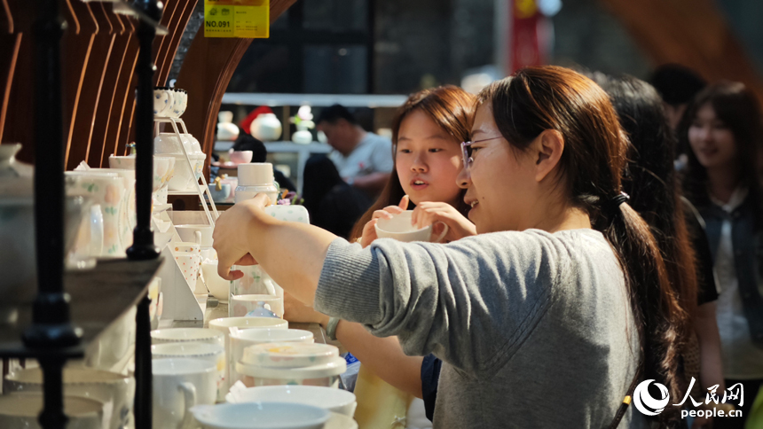 在陶溪川夜市，熙熙攘攘的人群穿梭于五百余攤位間，煙火氣與藝術氛圍升騰，繪就一幅熱鬧非凡的市井長卷。人民網 涂詩軒攝
