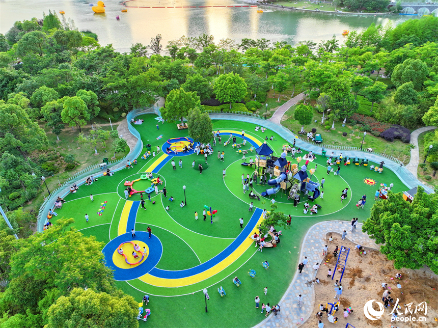 贛州市中心城區的一處公園里，家長帶著孩子在兒童游樂園內游玩，樂享親子時光。人民網 朱海鵬攝