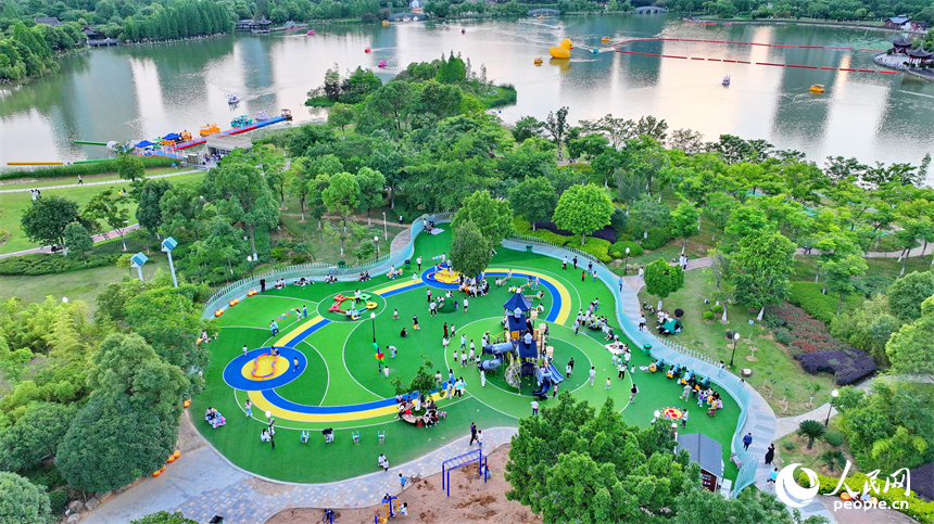 贛州市中心城區的一處公園里，家長帶著孩子在兒童游樂園內游玩，樂享親子時光。人民網 朱海鵬攝