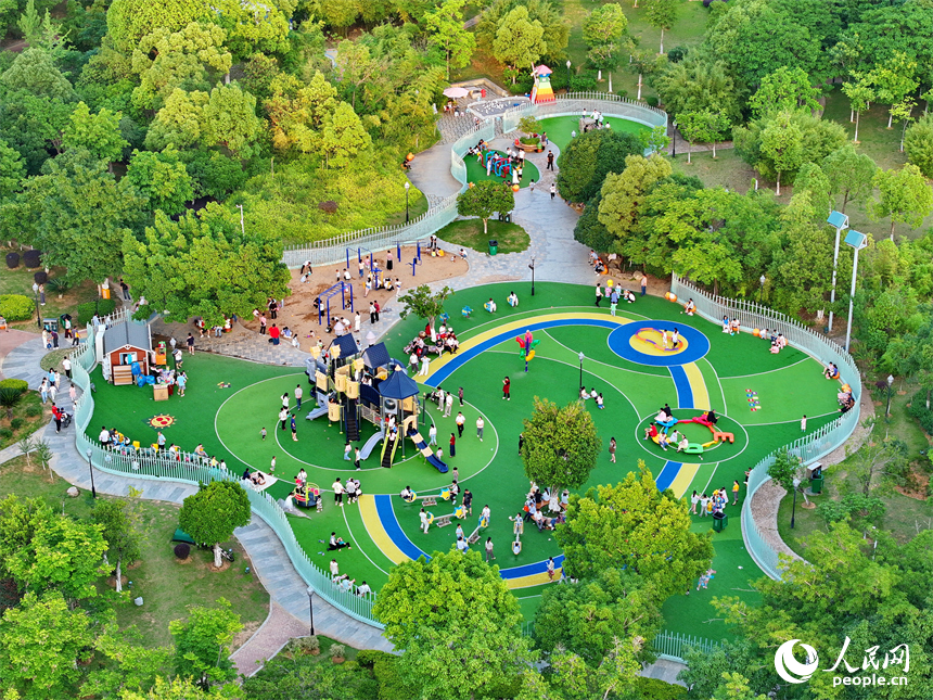 贛州市中心城區的一處公園里，家長帶著孩子在兒童游樂園內游玩，樂享親子時光。人民網 朱海鵬攝