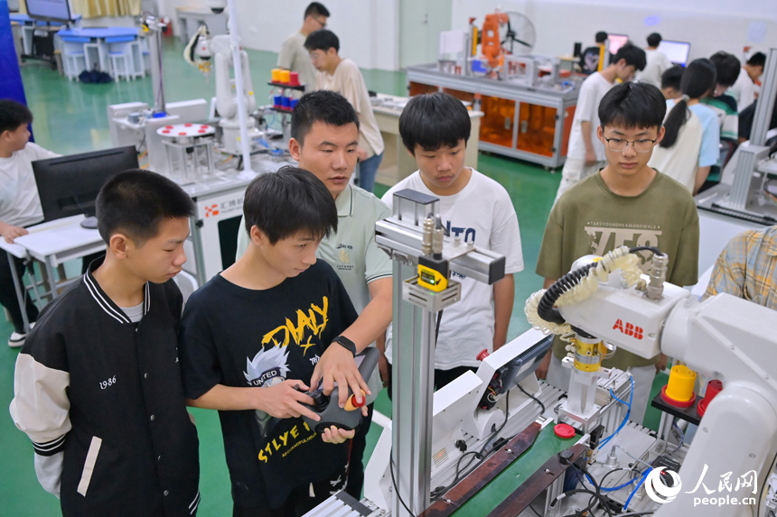 瑞金市瑞金中等專業學校工業機器人實訓基地，老師在指導學生在操作智能機械臂。人民網 朱海鵬攝