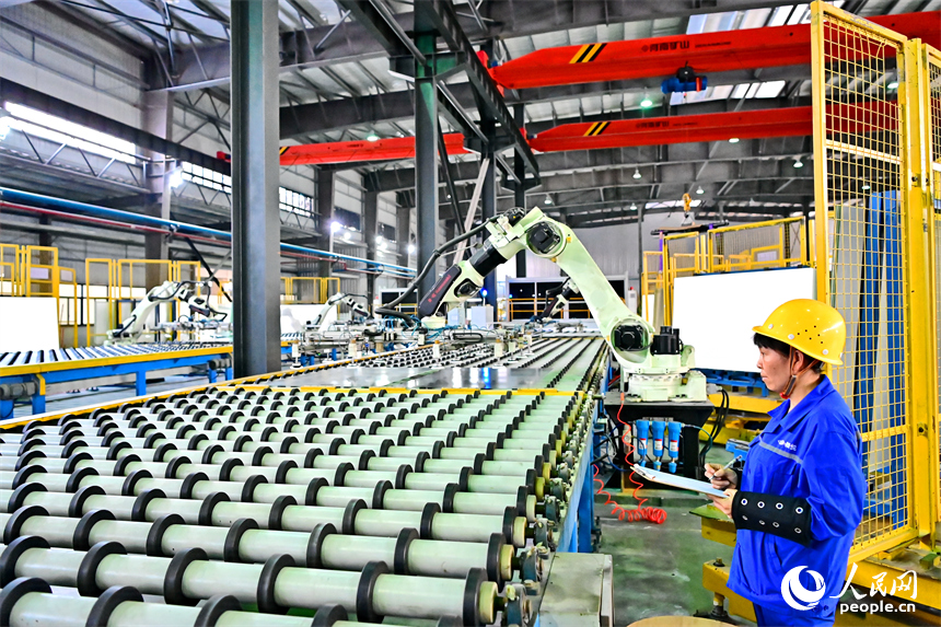 贛州市定南縣的一家新材料企業生產車間的智能機械臂有序運轉，工人在自動化產線上加工光伏玻璃。人民網 朱海鵬攝