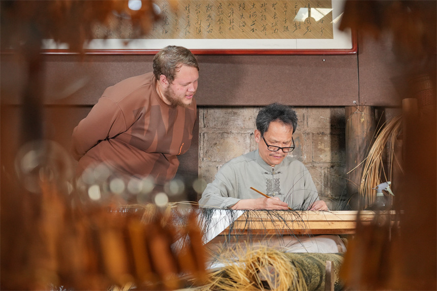 留學生白熙華正在查看徐建元編織的明代仇英版《清明上河圖》。人民網 孔文進攝