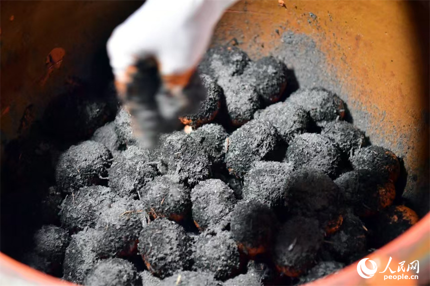 鴨蛋裹上黃泥入缸，均勻撒上草木灰后封缸腌制。人民網記者 時雨攝