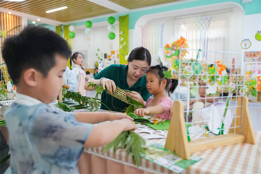 江西省撫州市臨川區保育院里，老師指導孩子們插艾籃。郭昊攝