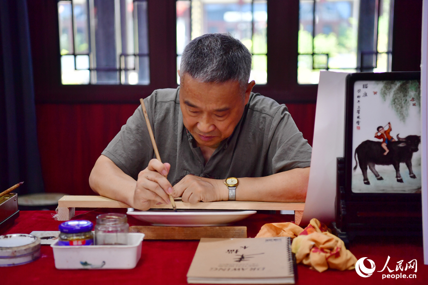 非物質文化遺產代表性傳承人正在集市現場展示瓷板畫技藝。人民網記者 時雨攝