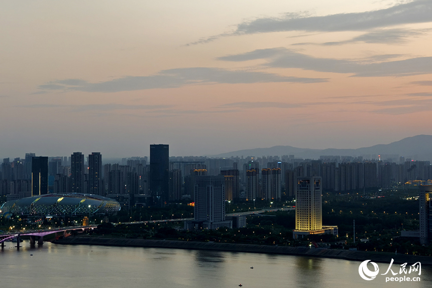 傍晚時分，染紅的天際映襯著梅嶺山脈，與城市初上的華燈相互輝映。人民網記者 時雨攝